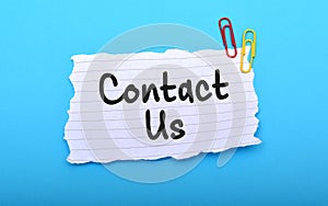 Contact us hand written on paper with blue background