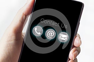 Contact us icons on smartphone with hand.