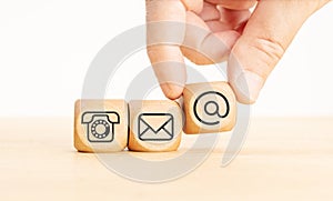 Contact us icons on wooden blocks. Hand holding a dice with communication icon