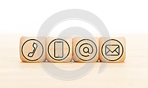 Contact us icons in wooden blocks on wooden desk. Copy space