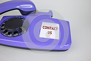 Contact us symbol. Old blue rotary dial telephone. Words `contact us`. Beautiful white background. Business and contact us conce