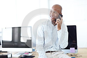 Contacting old business associates. a young businessman talking on the phone while sitting on a desk lined with