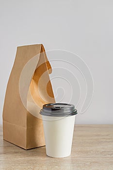 Contactless food delivery during. Mockup of dekivery service. Empty blank craft paper backage and disposable coffee cup on the