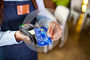 Contactless payment concept, female holding credit card near nfc technology on counter, client make transaction pay bill on