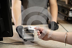 Contactless payment concept, woman customer holding credit card near nfc technology on counter, customer pays