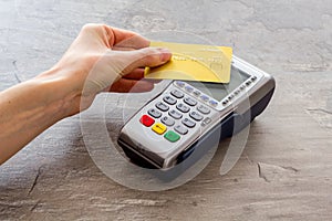 Contactless payment, paypass. Hand hold bank card near terminal on grey stone background