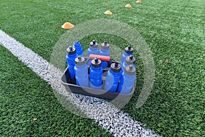 Container with blue sports water bottles for football field with sideline and chips.