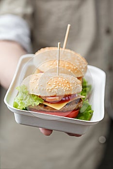 Container with burgers in male hand