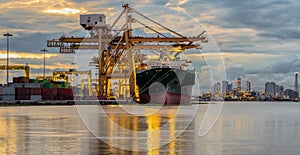 Container Cargo freight ship with working crane bridge in shipyard at dusk