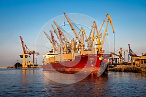 Container Cargo freight ship with working crane bridge in shipyard