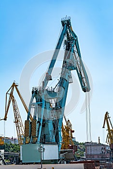 Container cargo freight ship with working crane bridge in shipyard at daytime