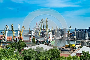 Container cargo freight ship with working crane bridge in shipyard at daytime