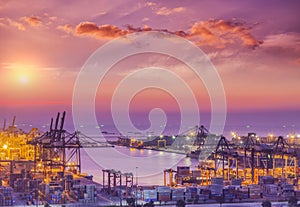 Container Cargo freight ship with working crane bridge in shipyard at dusk