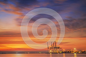 Container Cargo freight ship with working crane bridge in shipyard at dusk