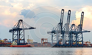 Container Cargo freight ship with working crane bridge in shipyard at dusk