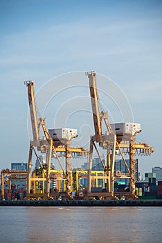 Container Cargo freight ship with working crane bridge in shipyard at dusk for Logistic Import Export