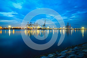 Container Cargo freight ship with working crane bridge in shipyard at dusk for Logistic Import Export background