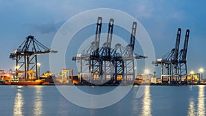 Container Cargo freight ship with working crane bridge in shipyard at dusk for Logistic Import Export background.