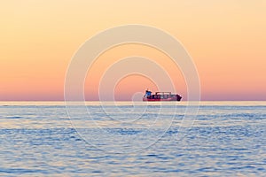 Container Cargo ship on the horizon at sunset