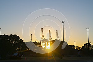 Container cranes on Port of Tauranga facility backlit by rising sun at Sulphur Point in city