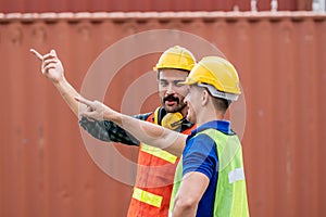 Container Depot chief  talking with foreman in safety vast and safety helmet in Container shipyard