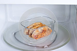 Container with food in the microwave. Cutlets in a container