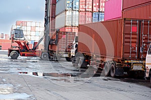 A container forklift sits behind a stack of containers