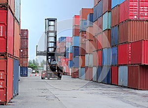 A container forklift sits behind a stack of containers