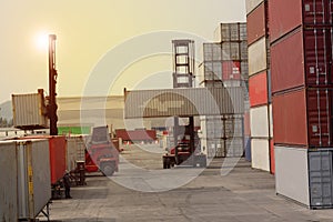 Container forklift truck in shipping yard for import export industrial logistics transport with container stacks in background