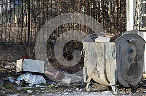 A container full of garbage near a recycling area