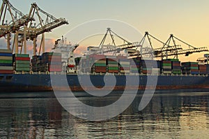 Container loading in cargo freight ship with industrial cranes. Container ship at industrial port of Koper