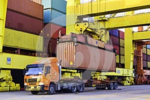 Container loading to a vessel, Quay crane pick up a container from trailer load onto a large container ship at a seaport.