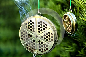 Container for mosquito-repelling incense on green background