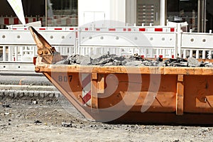 Container, orange skip for construction waste standing on the road, road construction work, construction site