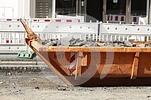 Container, orange skip for construction waste standing on the road, road construction work, construction site