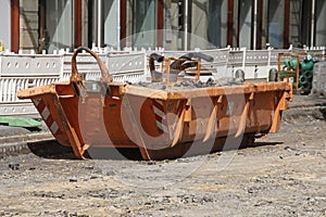 Container, orange skip for construction waste standing on the road, road construction work, construction site