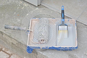 Container with paint roller and brush