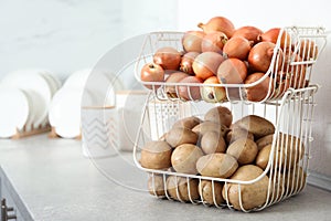 Container with potatoes and onions on grey kitchen counter. Orderly storage