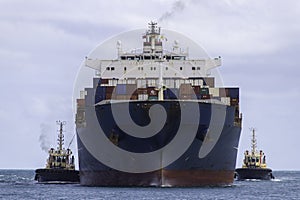 Container ship arriving port with assistance of two tugs