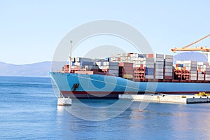 Container ship with containers to shore in port ship port on horizon / Cargo transportation by sea and goods unloading process.