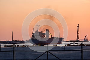 Container ship With cranes for loading goods in the port in the evening
