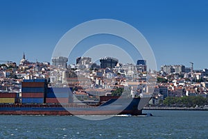 A container ship entering the port with the city of Lisbon skyline on the background