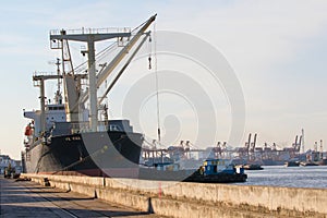 Container ship loading material goods from local ship in habor p