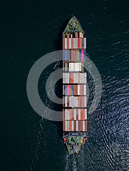 A container ship moves steadily through the ocean, carrying stacked containers