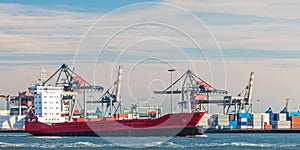 Container ship passing cranes in Rotterdam harbor