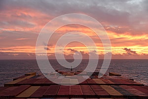 Container ship sailing through Atlantic Ocean toward beautiful sunrise.