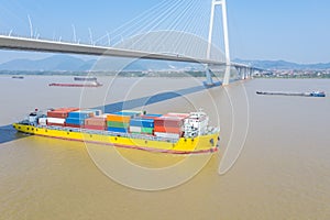 Container ship sailing on inland river under cable-stayed bridge