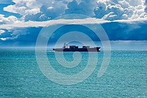Container Ship in the Sea under Cumulonimbus Clouds with Rain