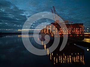 Container ship stern with lights at dusk Southampton Docks UK aerial closeup