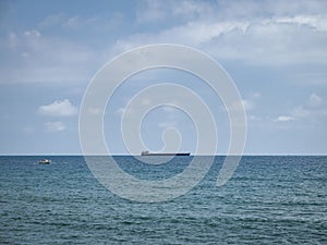 A container ship and a yacht on the sea horizon on the Mediterranean Sea off the coast of MÃ¡laga, Spain